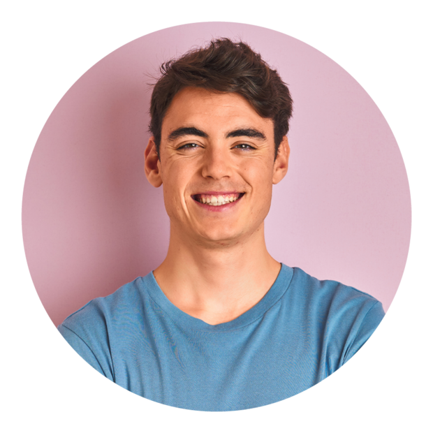 Krakenimages.com - stock.adobe.com Teenager-Junge in lässigem T-Shirt steht vor blauem Hintergrund, lächelt glücklich mit verschränkten Armen und schaut in die Kamera.